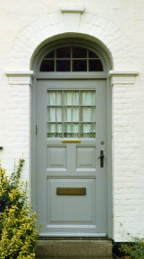 Original hoveddør med hvidmalede kapitæler og topsten, hvor dørportalens rulleskifte er synligt - Foto: Kurt Smith